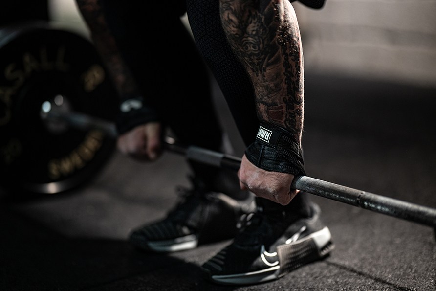 Lhikuva henkiln ksist ja  RAW Supps Figure 8 Lifting Strapseist kun hn on lhdss nostamaan levytankoa.